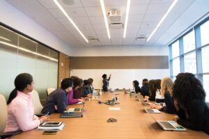 A woman gives a conference before an audience sitting around a long table