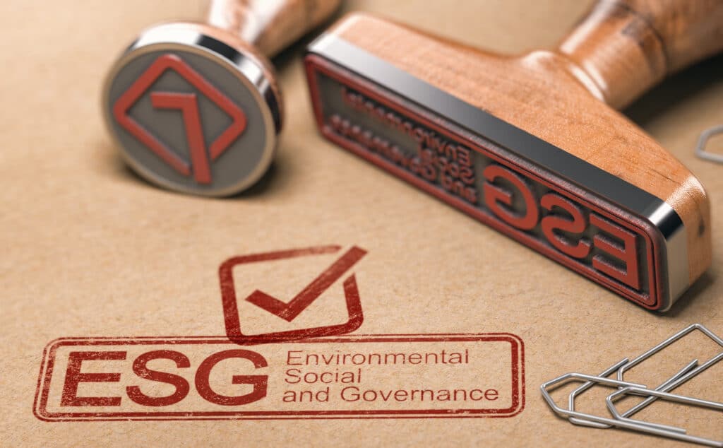 ESG, Environmental, Social and Governance printed in red with two rubber stamps over brown paper.